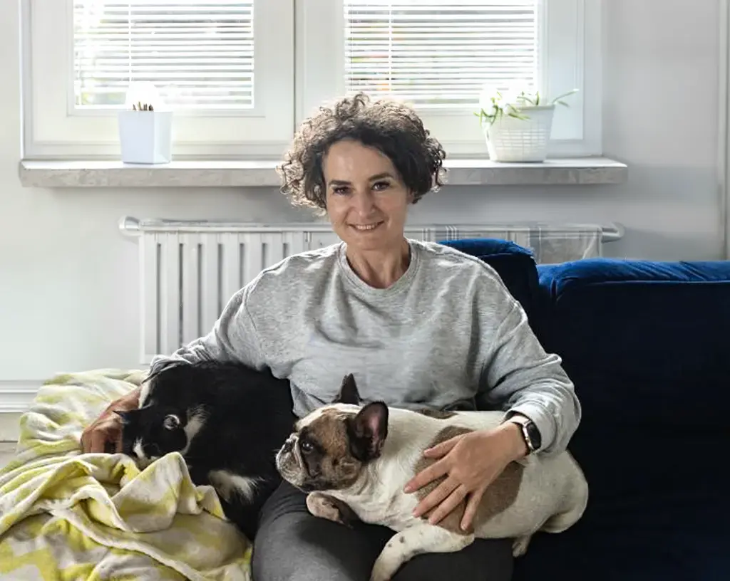 Psia Strefa_O mnie_Franek i Stella kobieta siedzi z psem i kotem na kolanach na kanapie